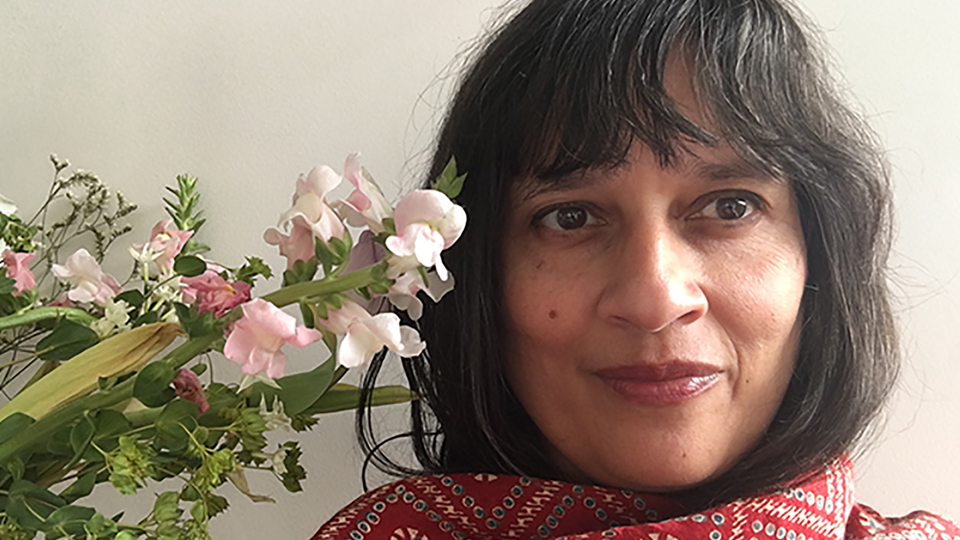 A photo of Bhanu Kapil next to some flowers